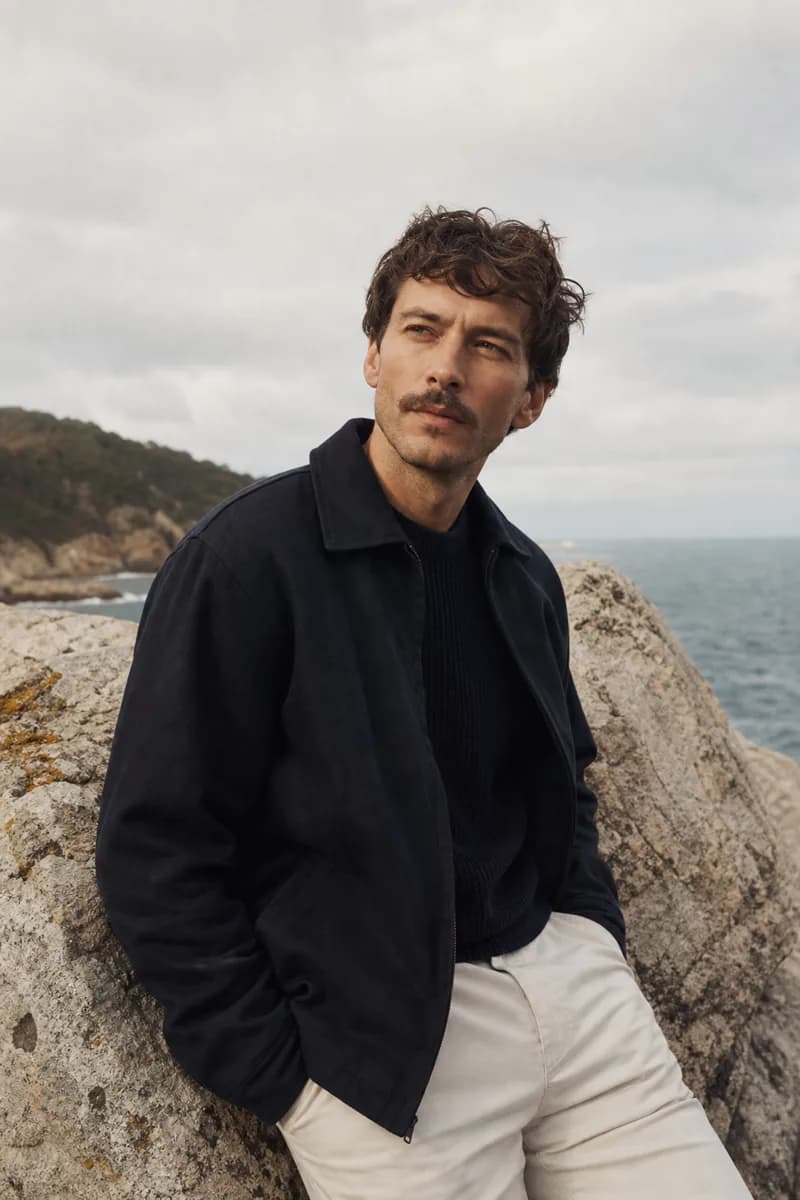 Coastal menswear editorial — navy jacket and cream chinos on the rocks