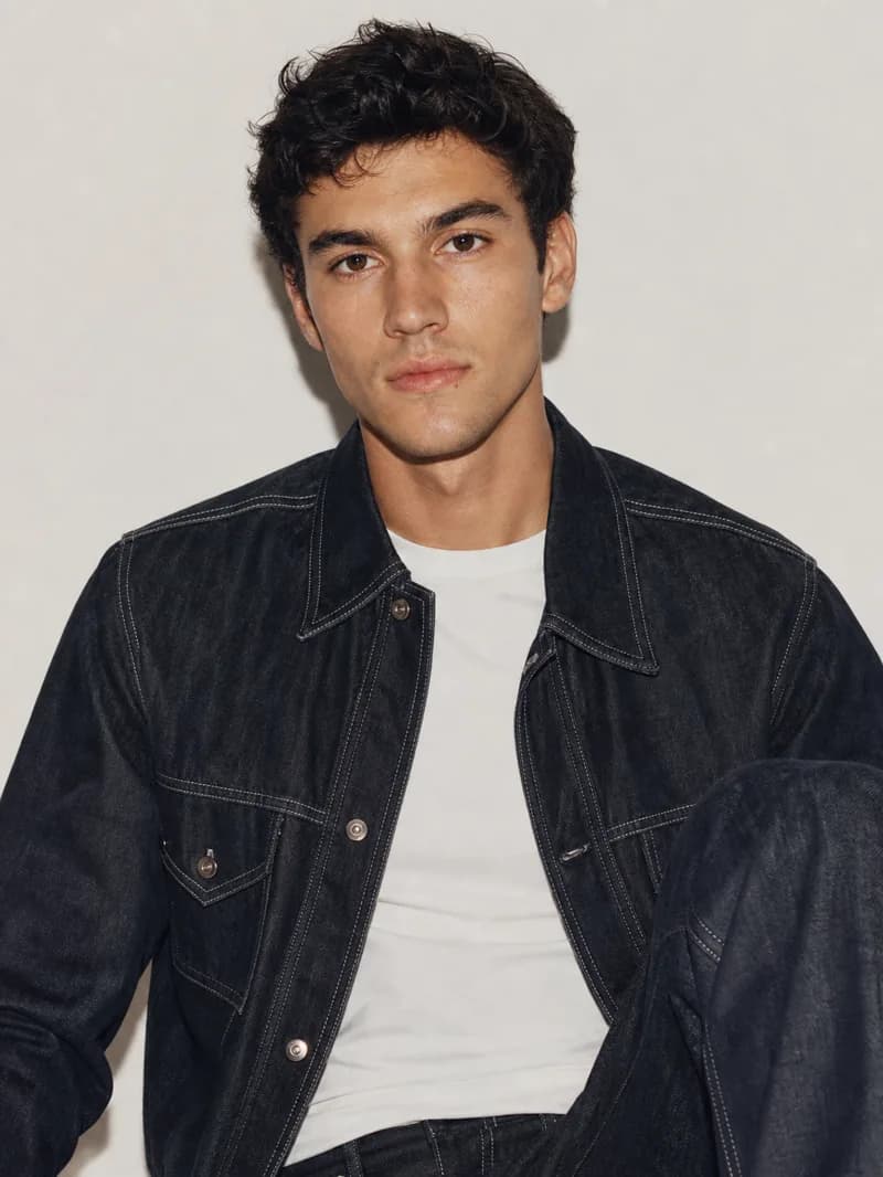 Seated menswear editorial portrait in a denim jacket and white tee