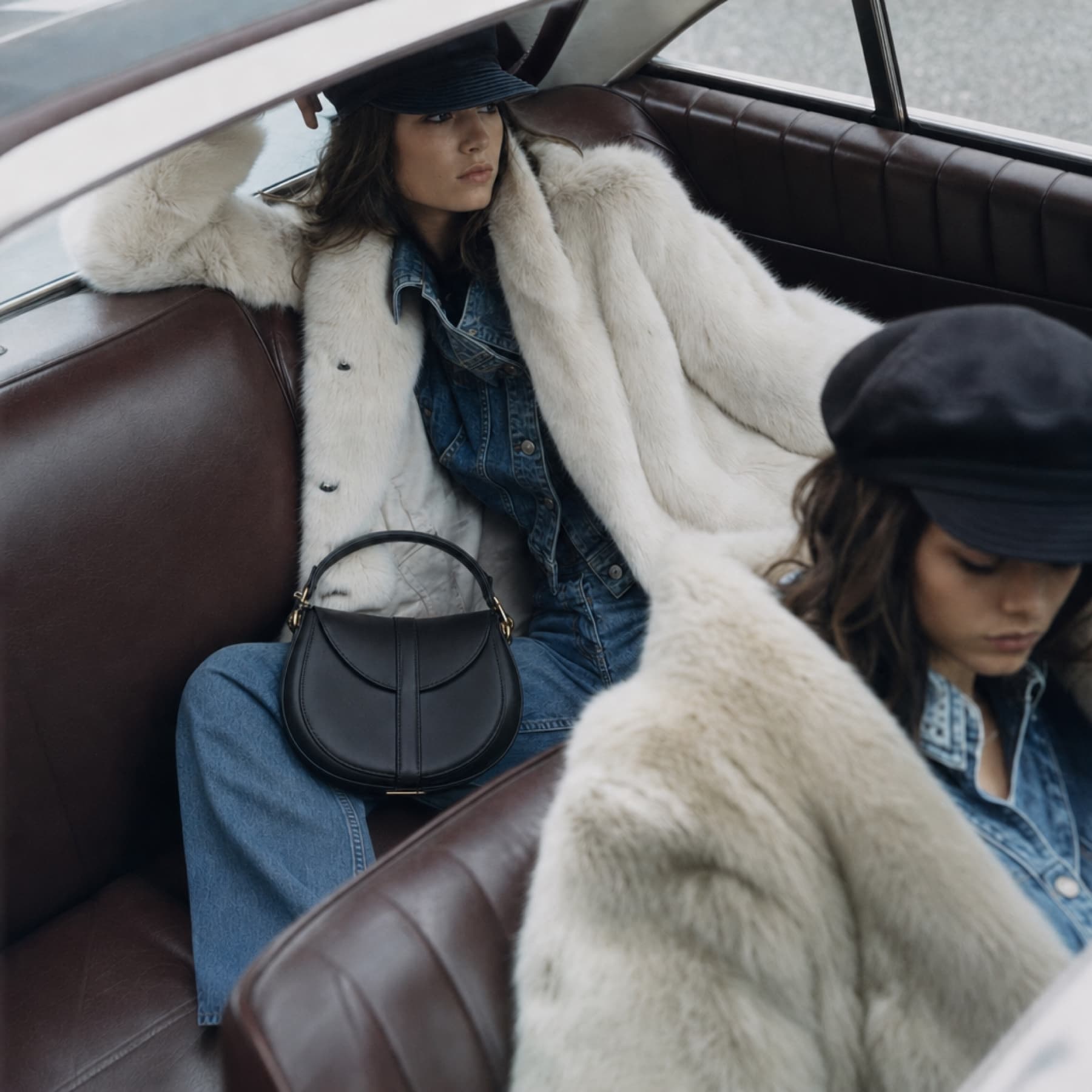 Fashion campaign with two models and a black handbag inside a vintage car