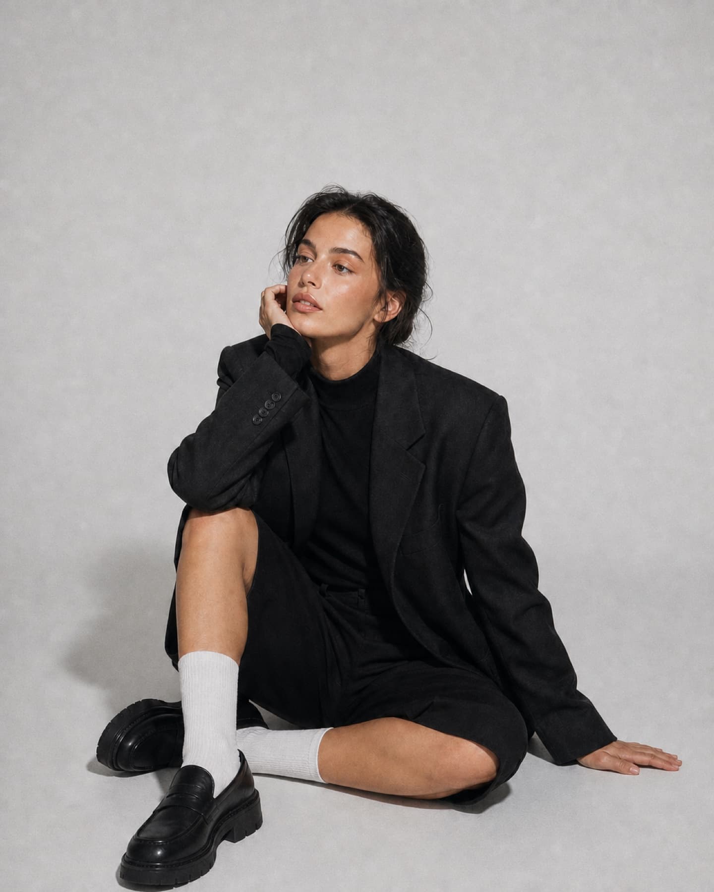 Fine-grain studio portrait with a seated model in black tailoring