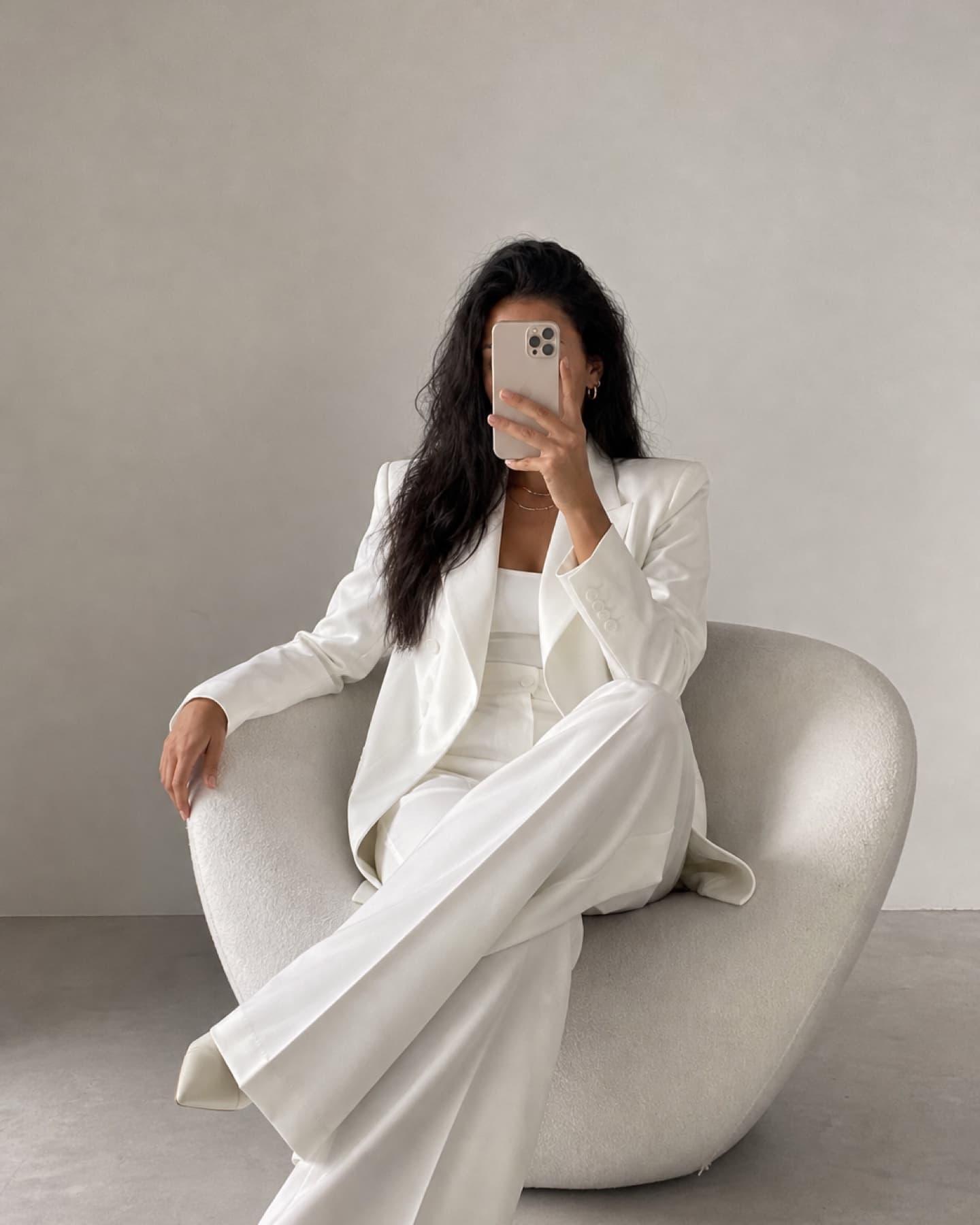 Minimal mirror selfie with a seated model in a white suit