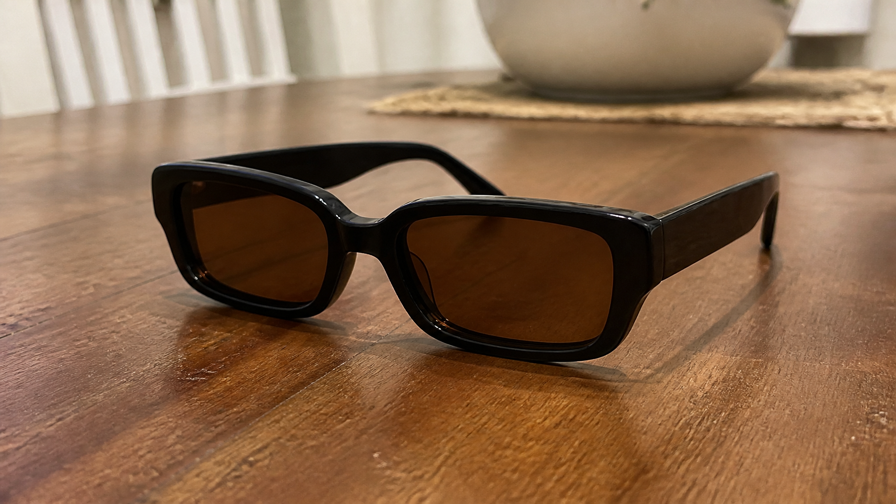 iPhone photo — black rectangular sunglasses with amber lenses on a home dining table